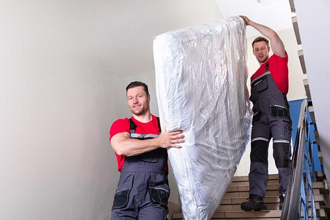 team of workers maneuvering a box spring through a doorway in Fair Oaks Ranch